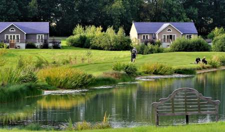 Wakes Hall Lodges with fishing lake and bench in the foreground