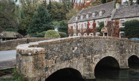 The ivy coloured The Swan Hotel behind a stone bridge