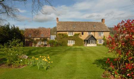 17th Century Cotswold stone farmhouse with open lawn and hedge borders