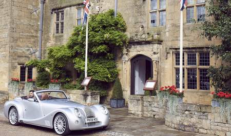 A vintage car parked in front of the Cotswold stone entrance to The Lygon Arms in the Cotswolds