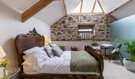 king size bed with a skylight over it stone wall in the background