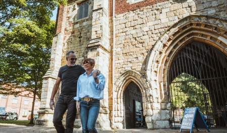 A couple strolling in the sunshine in front of the Bayle Museum in Bridlington's Old Town in East Yorkshire