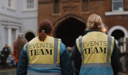 The back of two people walking towards North Bar, wearing hi vis jackets reading 'Events Team' on the back.