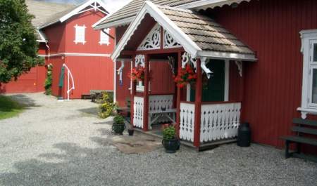 Inngangspartier på veslestua, med rød låve i bakgrunn