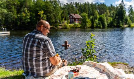 En mann som sitter på piknikpledd mens damen bader i bakgrunn
