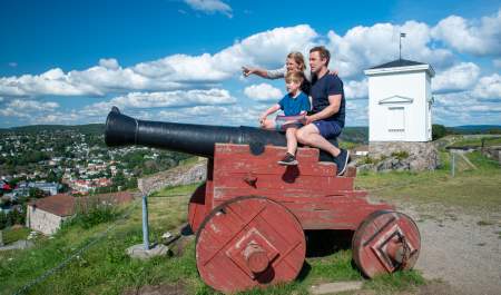 Familie som sitter på en kanon på Fredriksten festning i Halden.