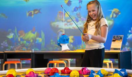Smilende jente som tester det store fiskespillet på INSPIRIA science center