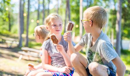 Tre barn sitter og spiser is