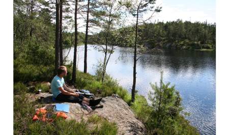 En gutt som sitter ved ett vann og titter utover