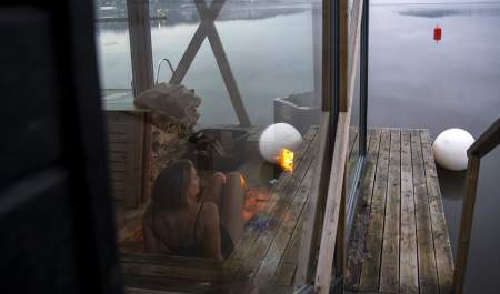 Kvinne sitter i en flytende badstu og ser utover vannet