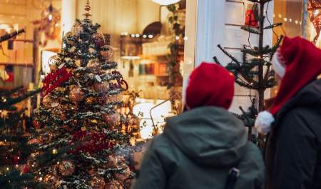 To personer med nisseluer ser på julepyntet butikkvindu