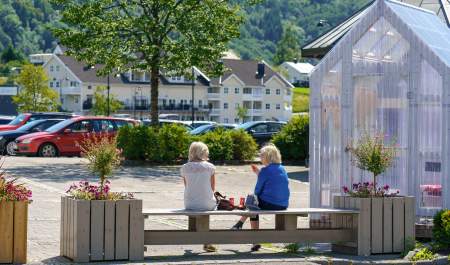 Spiser lunsj ved en benk i Liknes sentrum