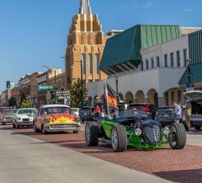 Parade with old-time cars driving down the street. The Stilfel Theatre in the background.