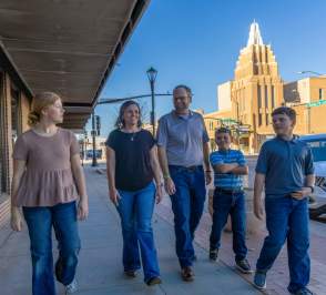 Family of five walking on the sidewalk downtown with the Stiefel Theatre behind them.