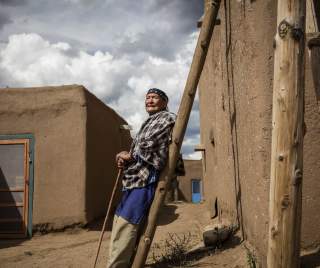 Man Leaning Against a Pole