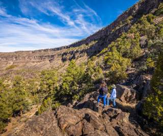 Two people in light hiking gear looking over a cragged landscape