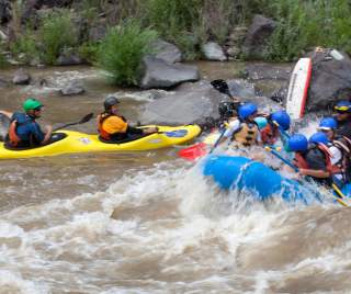 A group travels down the white-water rapids of the Rio Grande River via kayak and river raft.