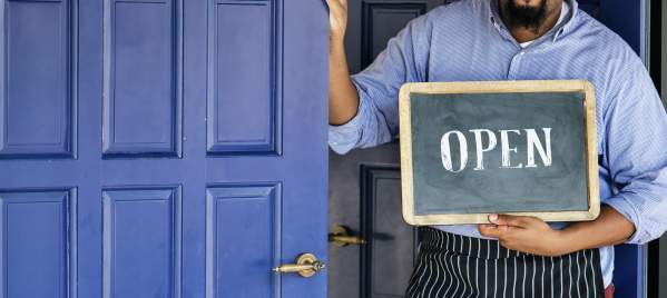 cheerful small business owner with open sign