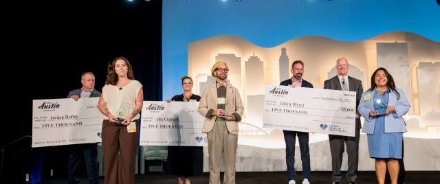 Three scholarship recipients standing on a stage in front of three people with giant scholarship checks.