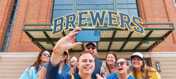 A group of Brewers fans smile in front of American Family Field