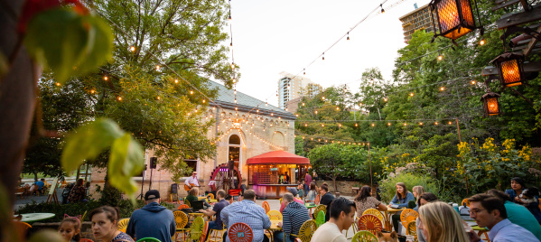Lively outdoor patio at Colectivo Coffee on the Lake with colorful chairs, string lights, trees, and people dining under evening light.