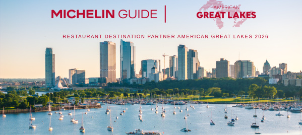 A waterfront view of Milwaukee’s skyline at sunset, with sailboats docked in the marina and a tour boat moving across Lake Michigan in the foreground. Above the skyline, red text reads “Michelin Guide | American Great Lakes” with the subheading “Restaurant Destination Partner American Great Lakes 2026.”