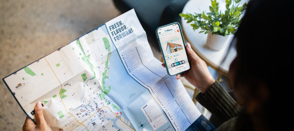A person holding an official visitors map of Milwaukee with a Map King App open.