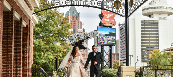 bride and groom holding hands, smiling, outside of Miller High Life Theatre