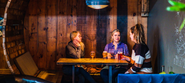 Three people sitting in a booth at Draft & Vessel in Wauwatosa