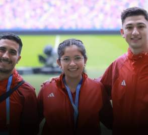 3 people wearing matching jackets and posing for the camera in front of a field