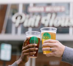 Two DORA cups cheersing in front of Urban's Pint House