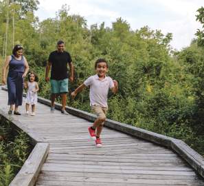 Kid running in front of his family on the boardwalk at Kiwanis Riverway Park