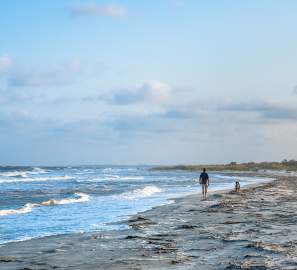 A beachgoer enjoys a walk along the shore of St. Simons Island beach
