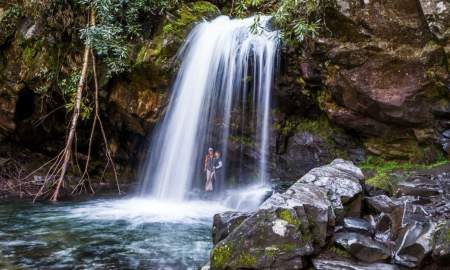 Hikers standing under the Grotto Falls on Trillium Gap Trail near Knoxville