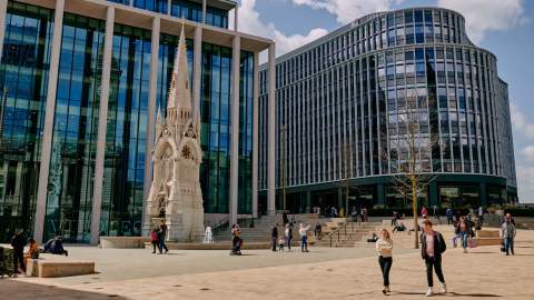 People walking around a renovated fountain in front of modern commercial buildings in Birmingham's Paradise