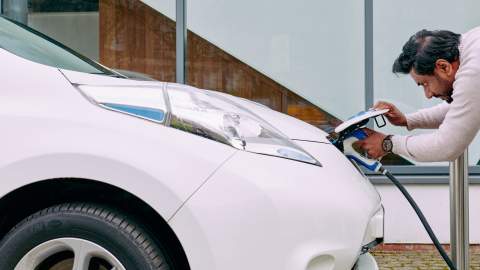 A man plugs in an electric car to charge
