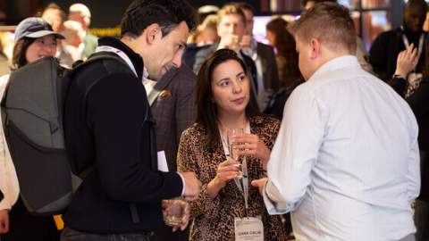 Three people with drinks network at an evening reception