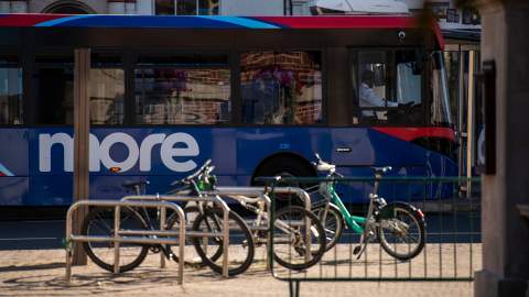 Blue bus in front cycles leaning on railings
