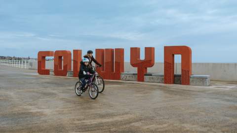 Cyclists going past the Colwyn sign