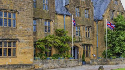 The honey-coloured Lygon Arms, in the Cotswolds, draped in wisteria with Union Jack flags flying