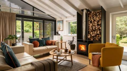 A modern lakeside property with the fire roaring facing the 2 sofas and armchair. Be.Here. in the Cotswolds