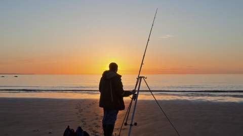 Man fishing on a beach in devon