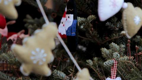 Handmade felt Christmas decorations hang from a Christmas tree.