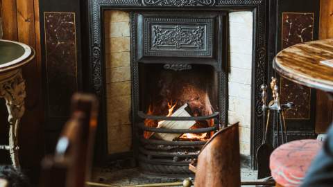 The inside of a cosy traditional pub, complete with real fire place.