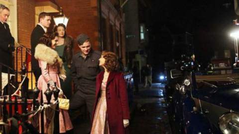 A still from A Royal Night Out filmed in Hull. Actresses and actors stand outside at night in 1940's style costumes.