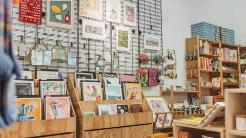 Interior of an Form Studio and studio in Hull displaying art prints, handmade gifts, stationery, books and homeware on wooden shelves and wall grids.