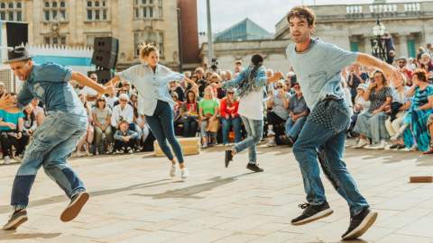 Freedom festival dancers perform in the sunshine in Queen Victoria Square with a crown surrounding them.