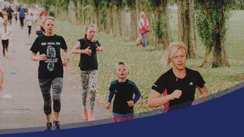 Runners along a path next to a row of Trees