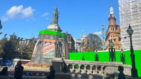 Queen Victoria Square in Hull decorated with wartime Blitz posters. Green screens encircle the square.