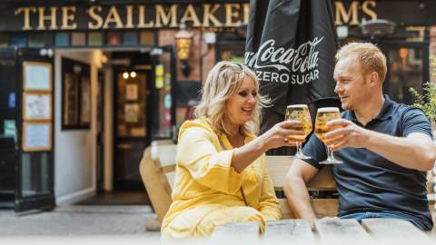 Two people enjoying drinks at an outdoor seating area in front of The Sailmaker Arms pub in Hull’s Old Town